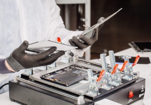 Close Up shot of male hands working with soldering iron on disassembling circuit board in mobile phone device.  Maintenance support and repairing service concept.