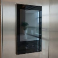 Modern stainless steel elevator interior with digital display panel.